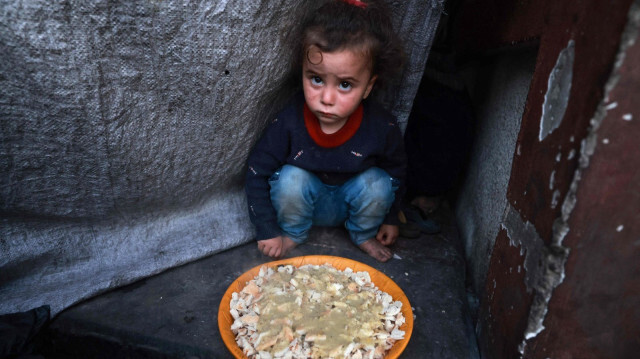 Палестинский ребенок сидит рядом с тарелкой перед трапезой ифтар, окончанием поста, на второй день священного месяца Рамадан в приюте для перемещенных лиц в Рафахе, на юге сектора Газа, Палестина, 12 марта 2024 года.