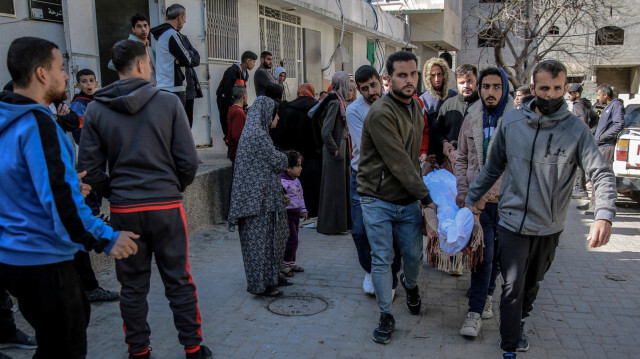 Des Palestiniens transportant le corps d'un homme tué lors d'un bombardement israélien depuis la morgue de l'hôpital Al-Shifa dans la ville de Gaza, le 15 mars 2024, dans le cadre du conflit entre Israël et le mouvement palestinien Hamas.