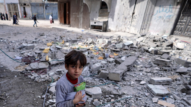 Un enfant palestinien s'accrochant à des denrées alimentaires récupérées au milieu des destructions causées par les bombardements israéliens à Bureij, dans le centre de la bande de Gaza, le 14 mars 2024, alors que la guerre entre Israël et le mouvement Hamas se poursuit.