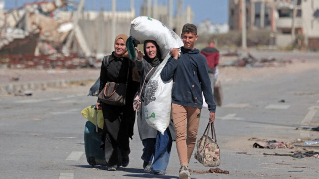 Des Palestiniens déplacés marchent sur une route près des décombres des maisons détruites par les bombardements israéliens dans la zone de Nuseirat, dans le centre de la bande de Gaza, le 15 mars 2024.