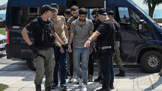 Un groupe de 13 migrants pakistanais et syriens accusés d'entrée illégale et de tentative d'incendie est escorté au palais de justice avant leur audience à Alexandroupoli, le 25 août 2023. 