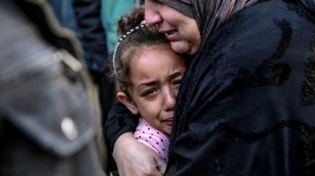 Une femme palestinienne tient un enfant alors qu'ils pleurent leurs proches tués dans les bombardements israéliens devant la morgue de l'hôpital Al-Shifa dans la ville de Gaza le 15 mars 2024.