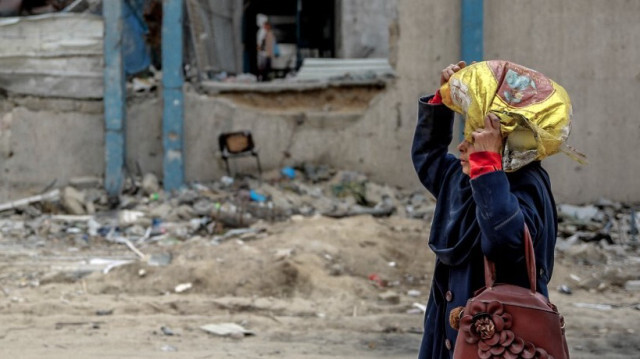 Une femme porte un sac de farine après la distribution de l'aide humanitaire dans la ville de Gaza le 17 mars 2024.