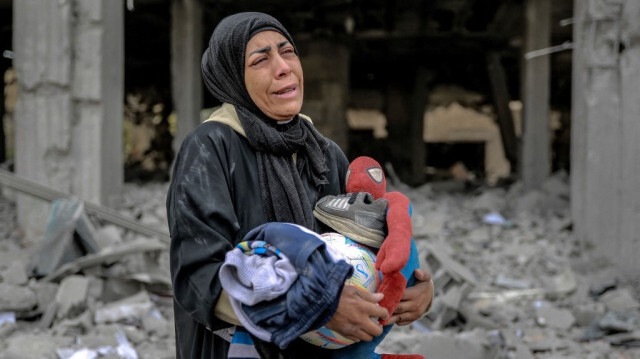 Une femme palestinienne réagit en tenant ses affaires à côté des décombres d'un bâtiment détruit par une frappe israélienne la nuit précédente, dans le quartier de Rimal à Gaza City, le 16 mars 2024.