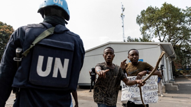 Un soldat de l'ONU est vu alors que des manifestants portent une affiche contre la mission de maintien de la paix en République démocratique du Congo (MONUSCO) dans les installations de l'ONU à Goma, le 25 juillet 2022. 