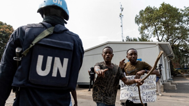 Un soldat de l'ONU est vu alors que des manifestants portent une affiche contre la mission de maintien de la paix en République démocratique du Congo (MONUSCO) dans les installations de l'ONU à Goma, le 25 juillet 2022.