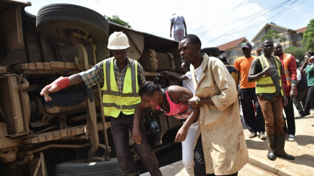 Des hommes aident une femme blessée à s'éloigner de l'épave d'un bus qui s'est renversé sur le côté suite à une collision avec un camion, à Nairobi, le 12 janvier 2018. 