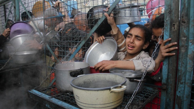 Des enfants Palestiniens attendent de la nourriture, distribuée par des organisations d'aide humanitaire, alors que les attaques israéliennes se poursuivent dans la Bande de Gaza, le 18 mars 2024.