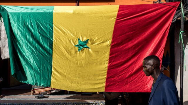 Un supporter passe devant un drapeau sénégalais avant le meeting de campagne du leader de l'opposition Ousmane Sonko et du candidat à la présidence de la coalition Diomaye Président Bassirou Diomaye Faye à Cap Skirring, au Sénégal, le 16 mars 2024. 