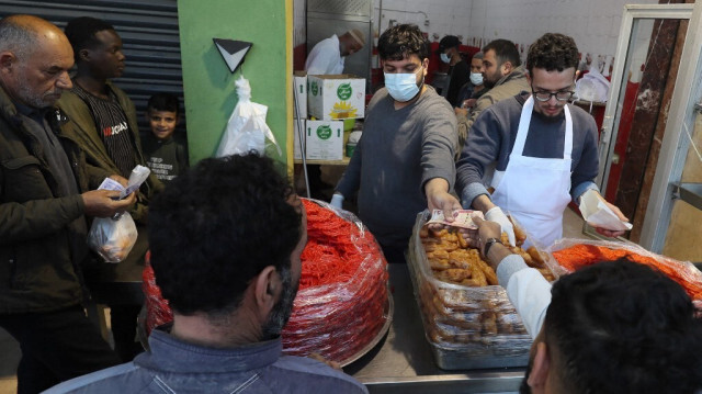 Des gens font la queue pour acheter du sfinz, un pain frit spongieux qui peut être servi nature ou avec des œufs, à Tripoli le 14 mars 2024, pendant le mois de jeûne musulman du Ramadan.