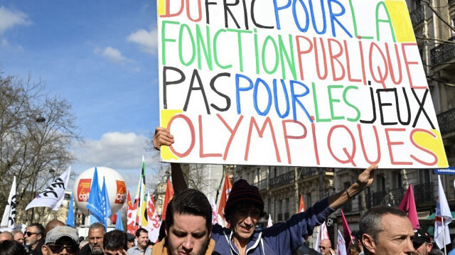 Le militant français Jean-Baptiste Redde, connu sous le nom de Voltuan, tient une pancarte lors d'une manifestation de la fonction publique dans le cadre d'un appel national lancé par les syndicats pour de meilleurs salaires, à Paris, le 19 mars 2024.