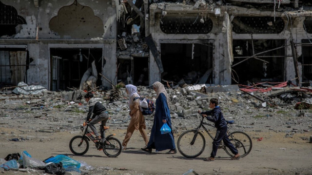 Des femmes et enfants Palestiniens marchent à côté de bâtiments détruits dans le nord de la bande de Gaza, le 21 mars 2024, dans le cadre des attaques devastatrices menées par l'armée israélienne. 