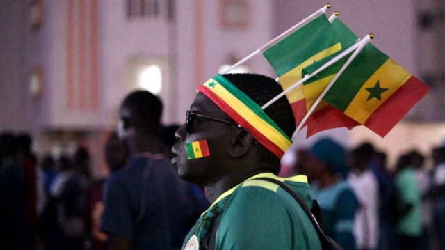 Un supporter sénégalais porte le drapeau national en regardant le match de football des huitièmes de finale de la Coupe d'Afrique des Nations (CAN) 2024 entre le Sénégal et la Côte d'Ivoire, dans la fan's zone de la Place de la Nation à Dakar, le 29 janvier 2024.