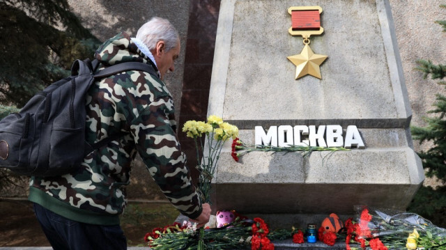 Un homme dépose des fleurs sur une pierre commémorative portant l'inscription "Moscou", à Sébastopol, en Crimée, le 23 mars 2024, en mémoire des victimes d'une attaque armée à la salle Crocus City Hall dans la ville de Krasnogorsk en Russie. 