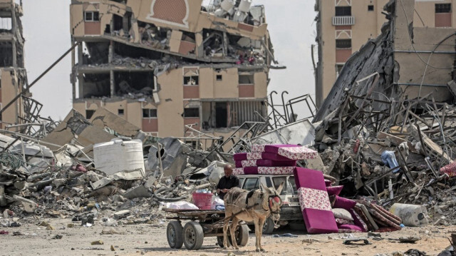 Un Palestinien déplacé avec ses affaires est assis sur une charrette à âne au milieu des décombres des maisons détruites par les bombardements israéliens dans la zone de Hamad, à l'ouest de Khan Yunis, dans le sud de la bande de Gaza, le 14 mars 2024.
