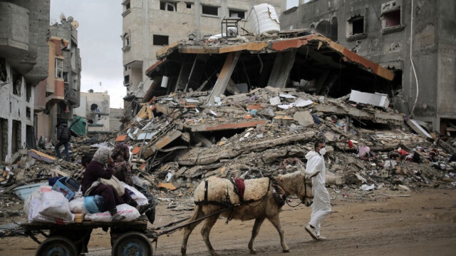 Des Palestiniens transportant certains de leurs biens sur une charrette tirée par un âne après être revenus brièvement à Khan Yunis, dans le sud de la bande de Gaza, pour vérifier ce qui reste de leurs maisons, le 7 mars 2024, dans le cadre des batailles entre Israël et le groupe militant palestinien Hamas.
