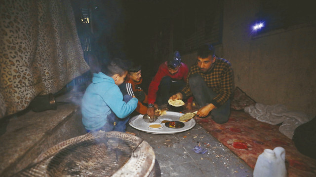 İsrail'in Gazze Şeridi'ne yönelik saldırıları sebebiyle evlerinden çıkarak Gazze'nin kuzeyindeki Selahaddin barınma merkezine sığınan Filistinli bir aile, zahter, biber sosu, birkaç parça ekmek ve çay ile sahur yapıyor.