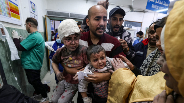 Un homme portant des enfants blessés par des bombardements israéliens à l'hôpital al-Najjar de Rafah, dans le sud de la bande de Gaza, le 24 mars 2024, dans le cadre du conflit entre Israël et le groupe militant Hamas.