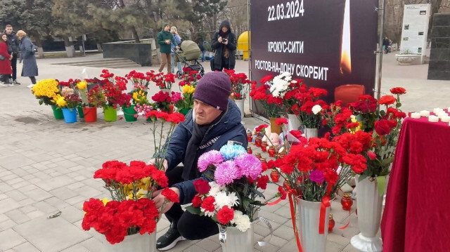 Un homme dépose des fleurs devant un mémorial improvisé à Rostov-sur-le-Don le 23 mars 2024, au lendemain d'une attaque à l'arme à feu contre l'hôtel de ville de Crocus, à Krasnogorsk, en Russie.