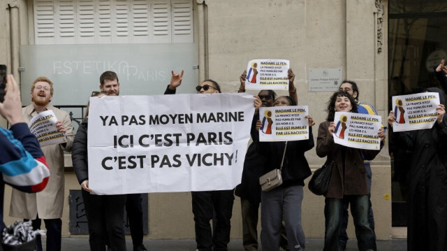 Les manifestants posent avec une banderole portant l'inscription "Il n'y a pas de moyen, Marine, ceci est Paris, pas Vichy" lors d'un rassemblement devant le siège du Rassemblement National (RN), organisé par l'association française SOS Racisme à Paris le 24 mars 2024, en soutien à Aya Nakamura. 