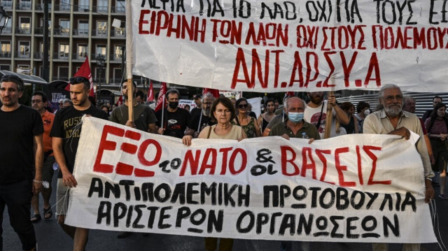 Des manifestants tiennent une banderole sur laquelle on peut lire "Non à l'OTAN, non aux bases militaires" lors d'une protestation contre l'alliance de défense de l'OTAN, dans le centre d'Athènes, le 29 juin 2022.