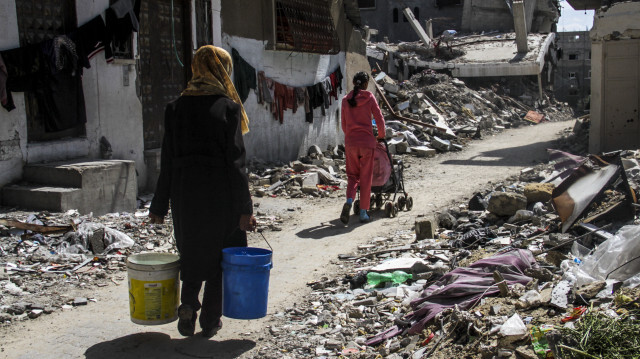 Une femme Palestinienne porte des sceaux d'eau dans un contexte de crise d'eau potable et de nourriture en raison des attaques israéliennes et du blocus imposé par Israël, le 23 mars 2024 à Jabalia, Gaza.