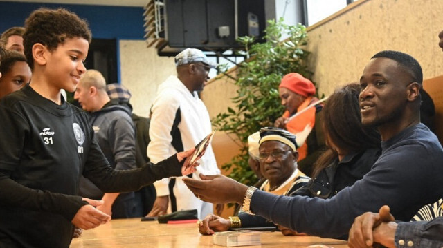 L'entraîneur de l'équipe nationale ivoirienne de football, Emerse Fae (à droite), signe des autographes dans le quartier populaire de Malakoff à Nantes, où il a grandi, le 28 février 2024.