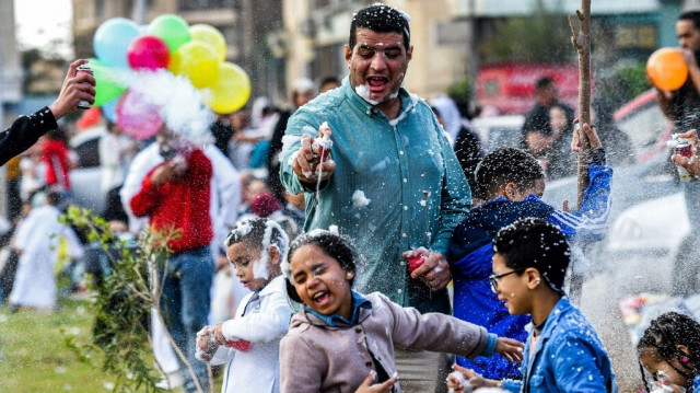 Des fêtards musulmans s'aspergent de mousse après la prière le premier jour de l'Aïd Al-Fitr pour célébrer la fin du mois de jeûne du Ramadan devant la mosquée égyptienne Al-Seddiq au Caire, le 21 avril 2023.