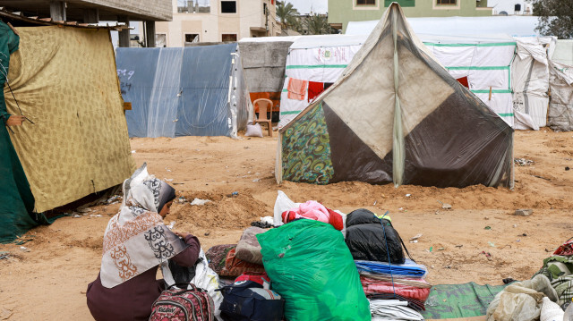 Le 13 février 2024, une femme assise à côté de ses affaires près d'une tente dans un camp avant de fuir Rafah, dans le sud de la bande de Gaza, en direction du centre du territoire palestinien.