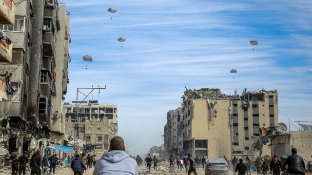 Des Palestiniens courant le long d'une rue alors que de l'aide humanitaire est larguée dans la ville de Gaza le 1er mars 2024. Depuis des mois, les travailleurs humanitaires mettent en garde contre une situation de plus en plus désespérée pour les civils de Gaza et, le 26 février, un responsable de l'office humanitaire des Nations unies (OCHA) a déclaré qu'une famine généralisée était "presque inévitable".