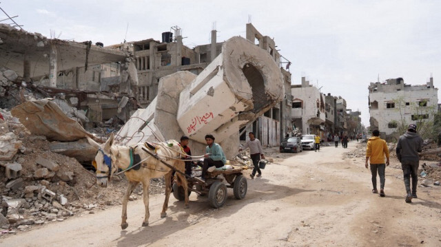 Des Palestiniens passent devant des bâtiments endommagés et détruits dans le camp de réfugiés palestiniens de Maghazi, dans le centre de la bande de Gaza, le 29 mars 2024.