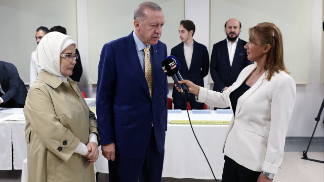 Le président turc Recep Tayyip Erdogan (C) et son épouse Emine Erdogan (G) s'exprimant après avoir voté pour les élections municipales dans un bureau de vote de l'école secondaire Saffet Cebi, à Istanbul, le 31 mars 2024.