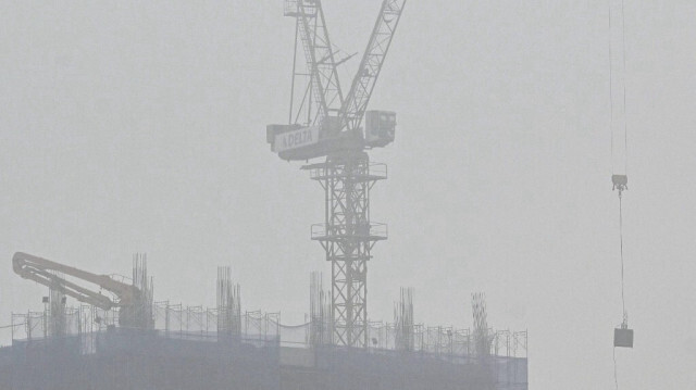 Une grue fonctionne sur un chantier de construction au milieu de niveaux élevés de pollution de l'air à Hanoï le 5 mars 2024.