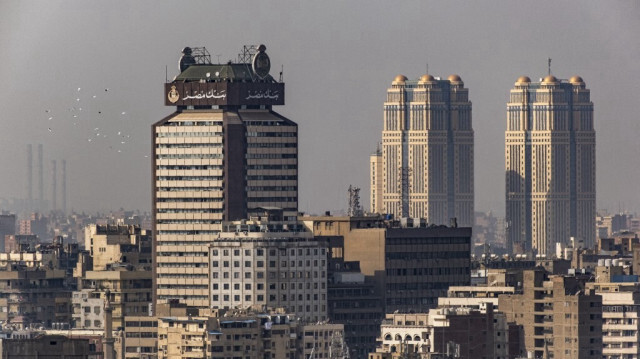 Une volée de pigeons passe devant l'immeuble commercial de grande hauteur (à gauche) qui sert de siège moderne à la Banque Misr (Bank of Egypt), la première banque égyptienne entièrement détenue par l'État (créée en 1920), au Caire, le 9 février 2023.