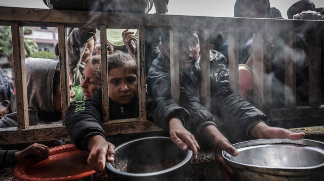 Des enfants palestiniens attendent pour recevoir un repas chaud préparé par des bénévoles dans la bande de Gaza, le 06 mars 2024.