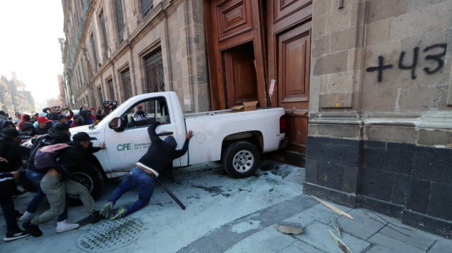 Des manifestants poussent une camionnette pour enfoncer la porte du palais présidentiel à Mexico, le 6 mars 2024, lors d'une manifestation sur la disparition de 43 étudiants de l'école de formation pédagogique d'Ayotzinapa en 2014.