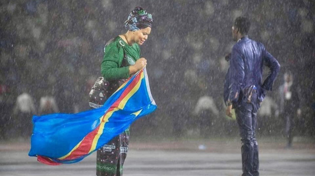 Une femme tenant le drapeau de la République démocratique du Congo se tient à côté d'un homme, sous la pluie.