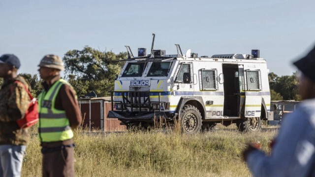 Un véhicule blindé de la police sud-africaine (SAPS) se tient près de structures informelles érigées dans un champ près du quartier de Lourier Park, à l'extérieur de Bloemfontein, le 6 mars 2024. 