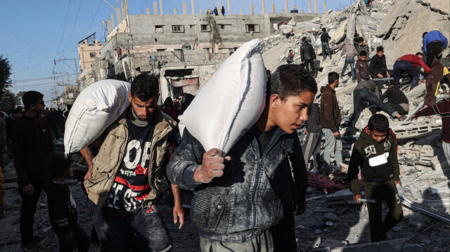 Des Palestiniens s'éloignant avec des objets récupérés dans les décombres d'un immeuble résidentiel touché par une frappe aérienne israélienne à Rafah, dans le sud de la bande de Gaza, le 9 mars 2023.
