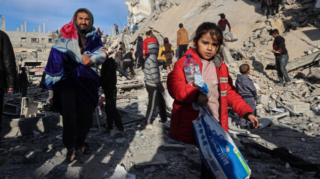Des Palestiniens s'éloignant avec des objets récupérés dans les décombres d'un immeuble résidentiel touché par une frappe aérienne israélienne à Rafah, dans le sud de la bande de Gaza, le 9 mars 2023.
