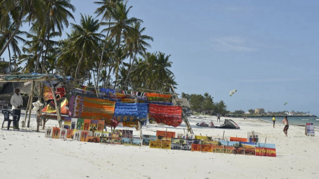 Un vendeur présente ses marchandises tandis qu'un touriste fait voler un cerf-volant sur la plage près de Mombasa, au Kenya, le 11 août 2017.