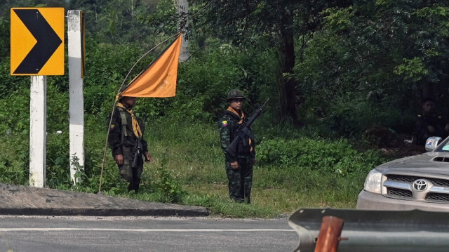 Cette photo prise le 24 septembre 2023 montrant des membres des forces frontalières de l'État Karen montant la garde sur le tronçon Yangon-Myawaddy de la route Asia Highway, près de la commune de Kawkareik. La section Myadawady-Yangon de l'Asia Highway ne fait que 400 kilomètres de long, mais elle serpente à travers des collines inondées par la pluie et sujettes aux glissements de terrain, et son trafic obéit au rythme des affrontements sporadiques entre les troupes de la junte et leurs opposants.