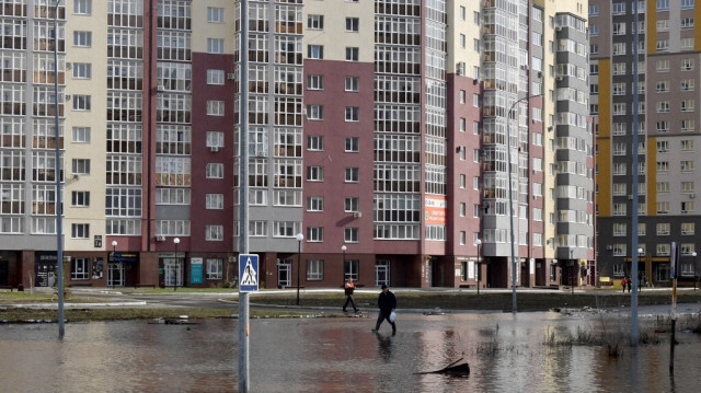 Un homme marche dans un quartier résidentiel inondé de la ville d'Orenburg le 13 avril 2024.