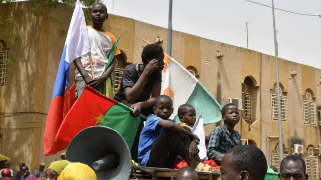 De jeunes garçons se rassemblant sur le toit d'une voiture tout en arborant des drapeaux du Niger, du Burkina Faso et de la Russie lors d'une manifestation pour le départ immédiat des soldats de l'armée américaine déployés dans le nord du Niger à Niamey, le 13 avril 2024. Des milliers de personnes ont manifesté le 13 avril 2024 à Niamey, la capitale du Niger, pour exiger le départ immédiat des soldats américains basés dans le nord du Niger, après que le régime militaire a déclaré qu'il se retirait d'un accord de coopération conclu en 2012 avec Washington.