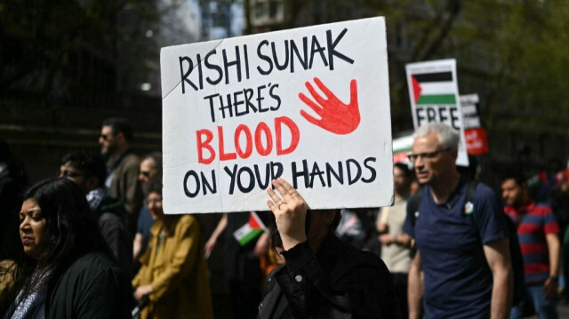 Un militant pro-palestinien tient une banderole sur laquelle on peut lire "Rishi Sunak, vous avez du sang sur les mains" lors d'une marche de protestation dans le centre de Londres, au cours d'une journée nationale d'action appelant à un cessez-le-feu dans la guerre entre Israël et le Hamas, le 13 avril 2024.