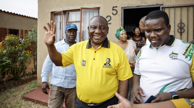 Le président du Congrès national africain (ANC) et président sud-africain Cyril Ramaphosa (C) saluant les habitants lors d'une campagne de porte-à-porte à Ekurhuleni le 10 mars 2024 avant les élections présidentielles sud-africaines prévues pour le 29 mai 2024.
