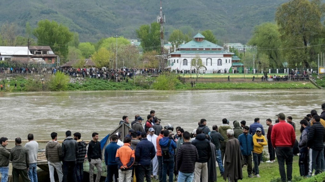 Les gens se rassemblent le long du bord de la rivière Jhelum alors que le personnel de la National Disaster Response Force mène une opération de recherche et de sauvetage après qu'un bateau avec des enfants s'est renversé à Srinagar le 15 avril 2024.