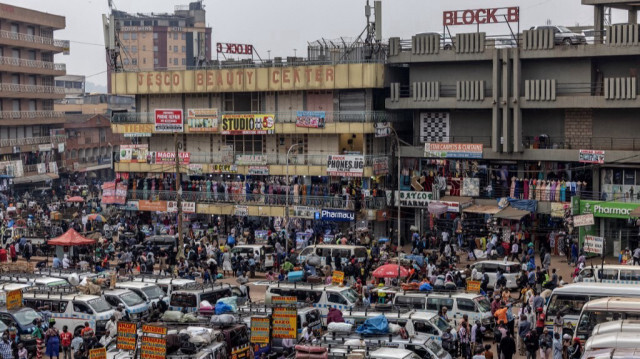 Des navetteurs marchent dans une zone commerciale très fréquentée à côté d'un arrêt de bus dans le centre de Kampala, le 22 janvier 2024.