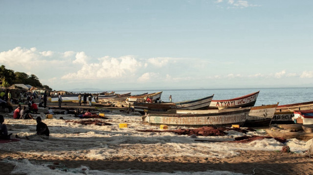 Des pêcheurs malawites fixent leurs filets de pêche alors que des bateaux de pêche sont vus sur la rive du lac Malawi dans le village de Senga, le 19 mai 2019 à Senga, au Malawi. 