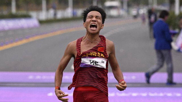 Le coureur chinois He Jie franchissant la ligne d'arrivée du marathon masculin lors des Jeux asiatiques 2022 à Hangzhou, dans la province orientale du Zhejiang en Chine, le le 5 octobre 2023. 